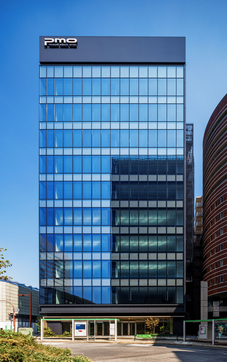 青空とビル外観： 雲一つない青空にそびえ立つ、全面ガラス張りの近代的なビル。